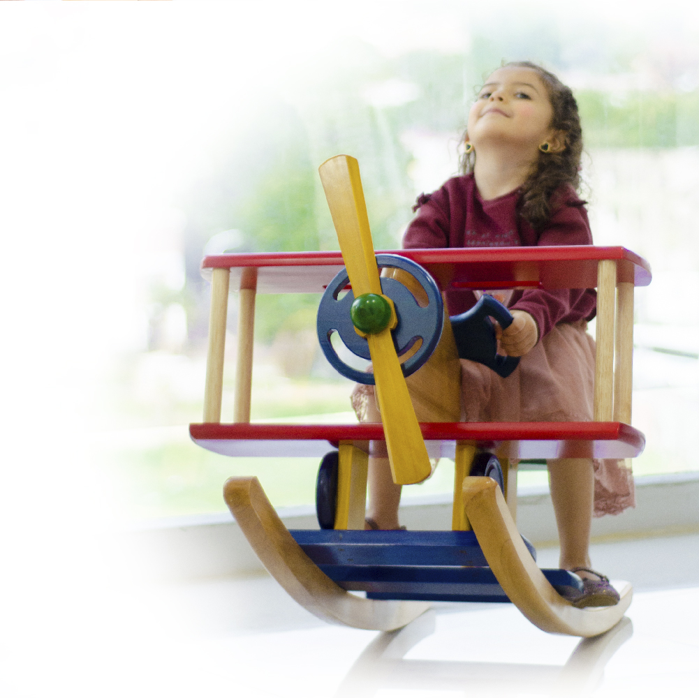 Niña jugando con avión de madera en consulta con pediatra en Bello